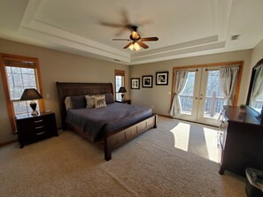 A bedroom with a queen-sized bed, a ceiling fan, a window with curtains, a nightstand, and framed pictures on the wall. - BONNIE'S-Lakefront-Very Nice Home! Neighborhood Boat Launch (Rogers)