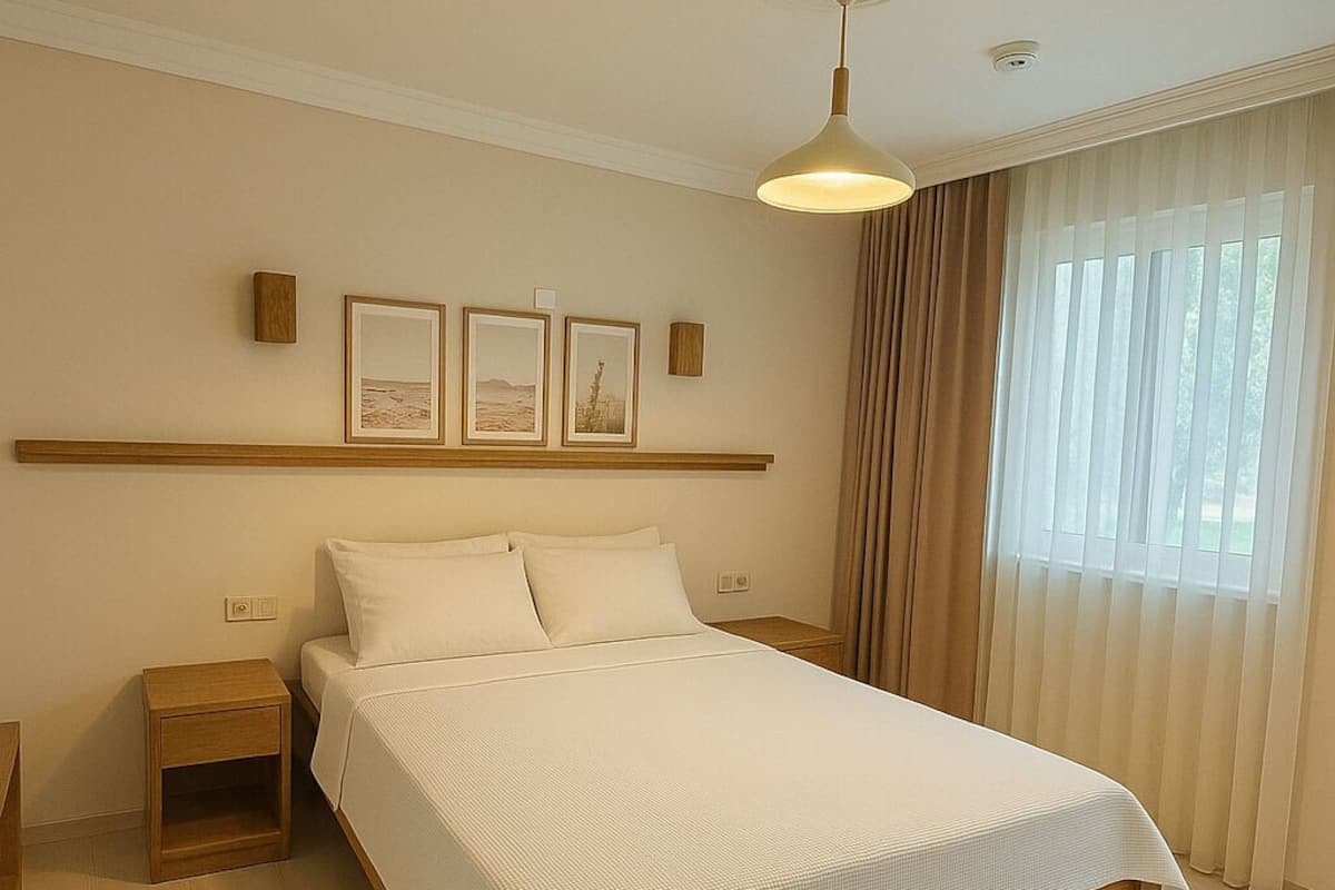 Une chambre d’hôtel avec un grand lit, des tables de chevet, un luminaire au plafond et des tableaux encadrés accrochés au mur.