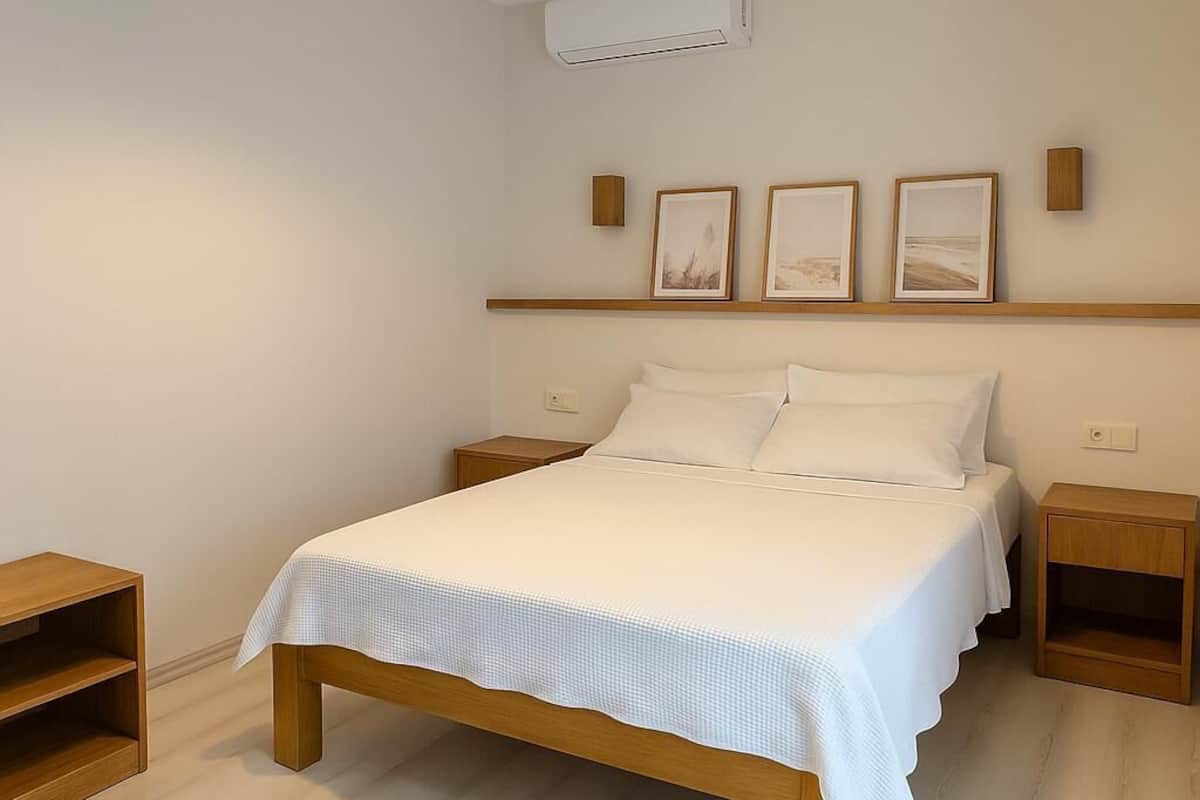 Une chambre à coucher avec un lit, des tables de chevet, un luminaire suspendu et des tableaux encadrés accrochés au mur.
