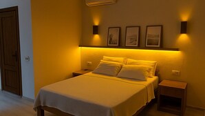Ein Schlafzimmer mit einem großen Bett, Nachttischen, einer Pendelleuchte und gerahmten Bildern an der Wand.