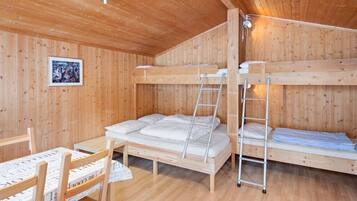 A wooden cabin with bunk beds, a table, and chairs.