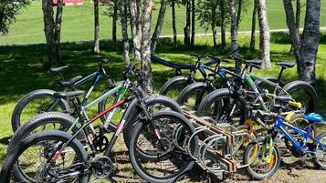 Una hilera de bicicletas estacionadas sobre césped, con árboles al fondo.