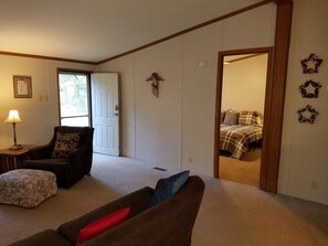 Cozy living space with a sofa, table, and lamp, surrounded by wall art and a carpeted floor.
