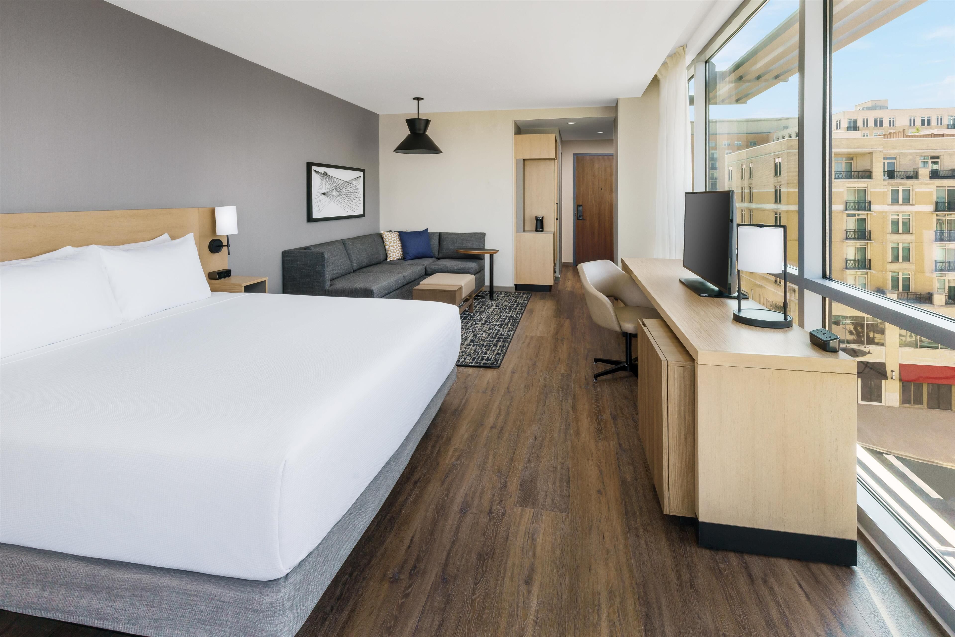 Habitación de hotel moderna con una cama grande, un sofá, un escritorio y un televisor.