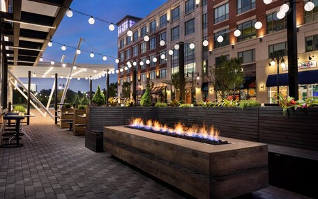An outdoor patio with a fire feature, string lights, and a seating area.