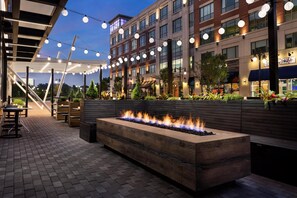 An outdoor patio with a fire feature, string lights, and a seating area. - Hyatt Place National Harbor (Oxon Hill)