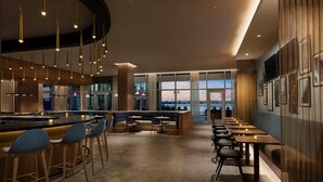 A modern bar area with a long counter, bar stools, and a seating area with tables and chairs. - Hyatt Place National Harbor (Oxon Hill)