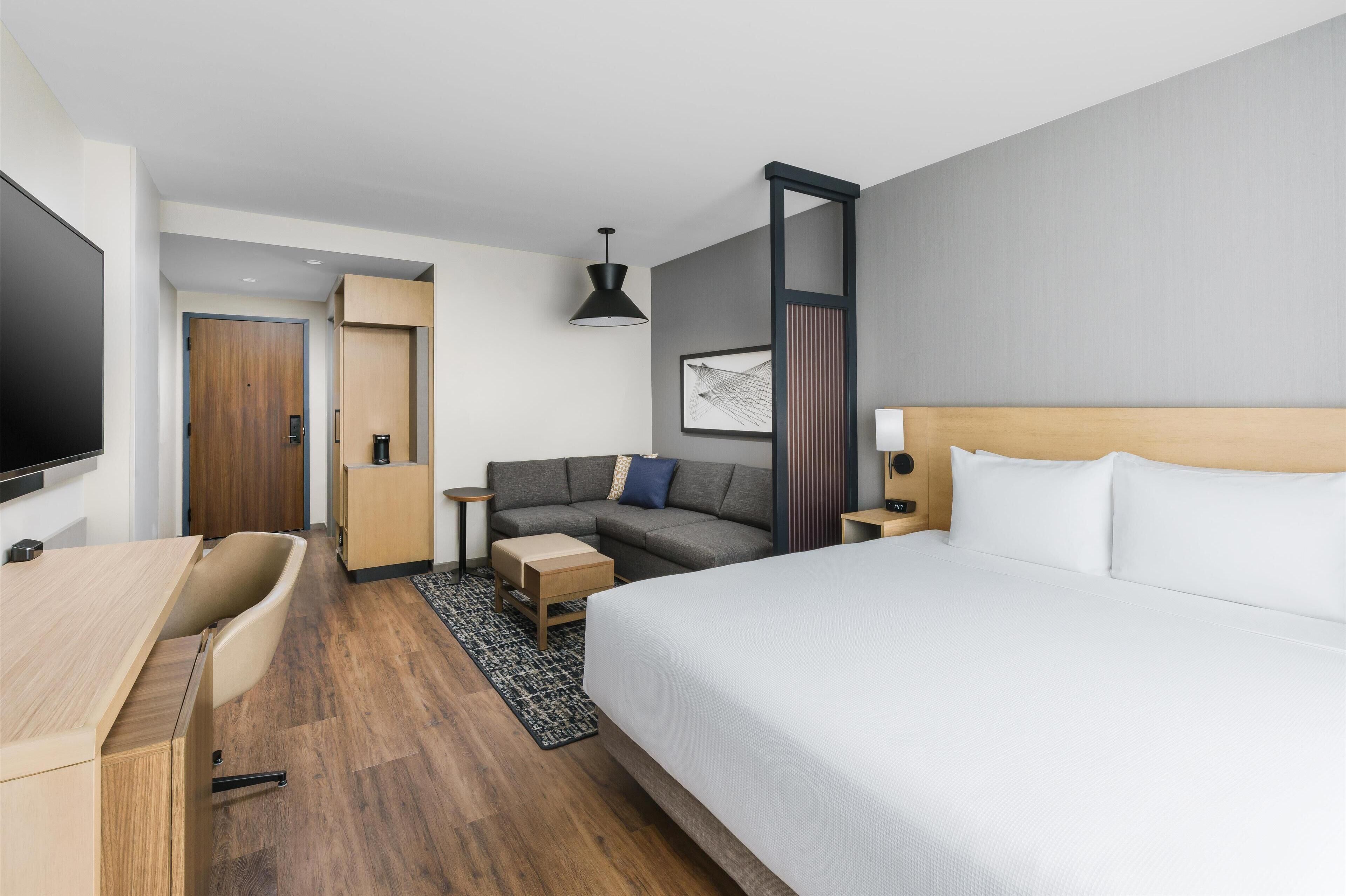 Una habitación de hotel moderna con cama, sofá, escritorio y televisor.