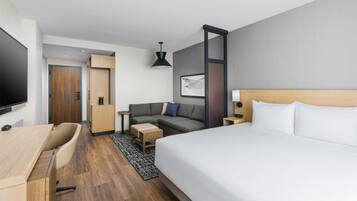 Una habitación de hotel moderna con cama, sofá, escritorio y televisor.