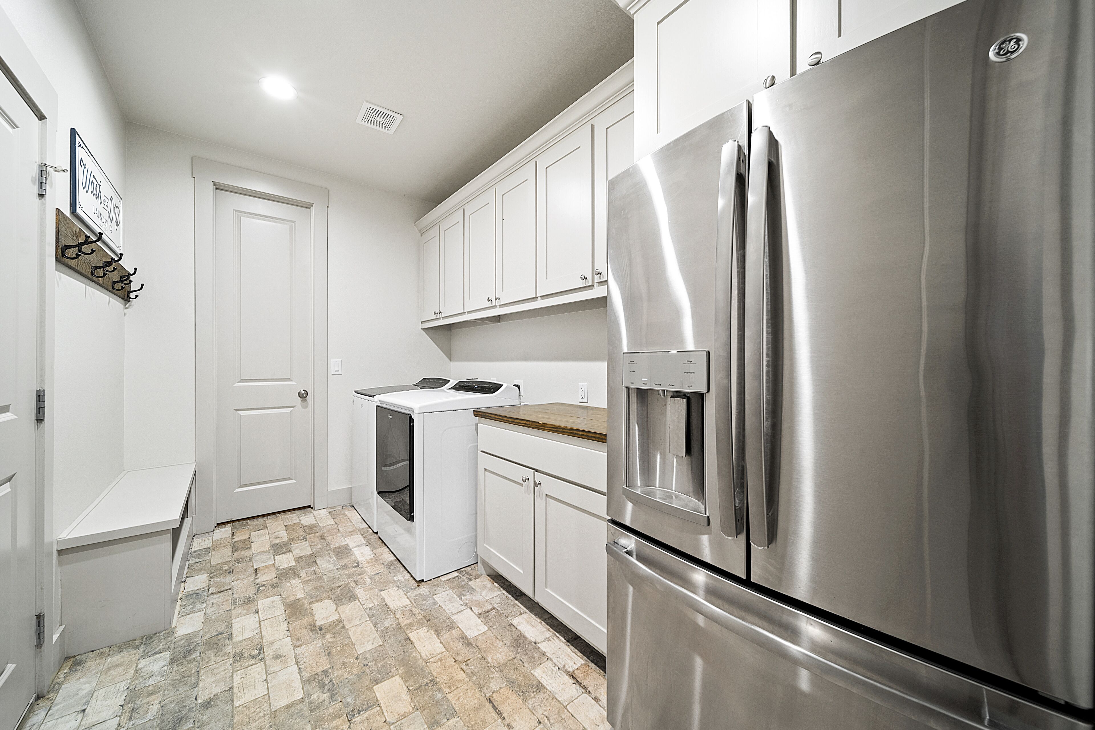 A kitchen with white cabinets, a stainless steel refrigerator, and a built-in oven.