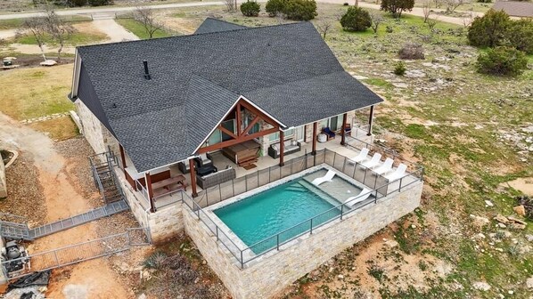 A two-story house with a large deck, a swimming pool, and a stone foundation.