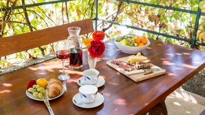 A wooden table set with a croissant, grapes, a bowl of fruit, cheese, and cured meats, accompanied by wine glasses and cups. - Countryside House With Pool - Vila Šore (Dugobabe)