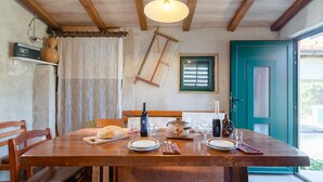 A dining area with a wooden table set for two, a loaf of bread, a bottle of wine, and a candle. - Countryside House With Pool - Vila Šore (Dugobabe)
