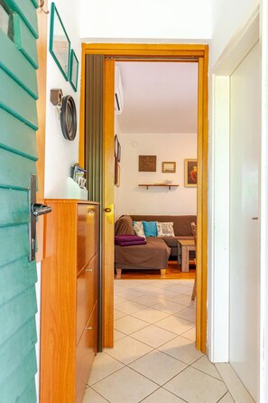 Een deur die leidt naar een woonkamer met een bank, een salontafel en een klein vloerkleed.