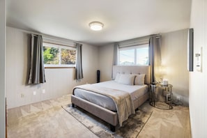 A bedroom with a bed, a nightstand, a window with curtains, and a ceiling light.