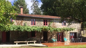 A stone house with red windows and doors, a wooden bench, and outdoor seating. - Beautiful stone house in tranquil, rural setting (Pontevedra)
