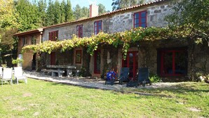 A stone building with red-framed windows and a covered porch. - Beautiful stone house in tranquil, rural setting (Pontevedra)