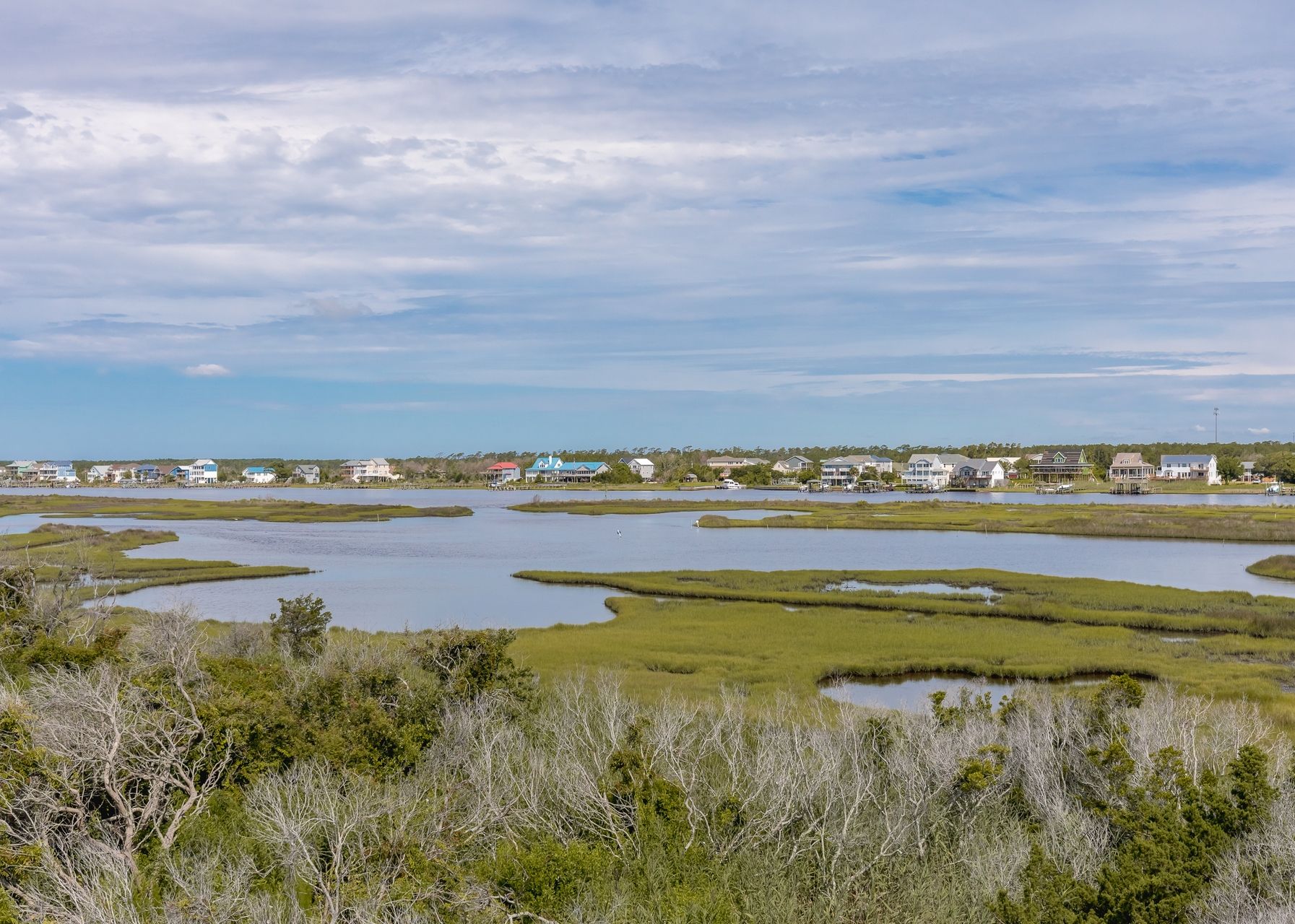 A coastal landscape with multiple water bodies and a row of houses.