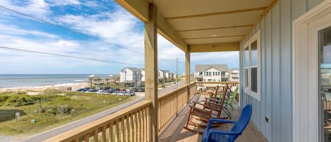 Une terrasse en bois offrant une vue sur la plage et l’océan.