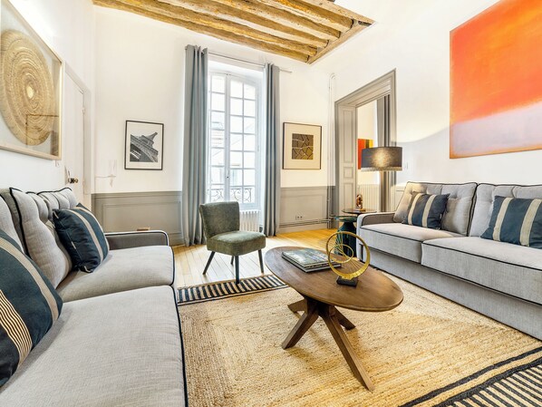 Una sala de estar con dos sofás, una mesa de centro, un sillón y un ventanal grande.