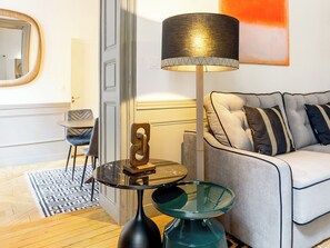 Una sala moderna con un sofá, una mesa de centro de vidrio, una lámpara de pie y un espejo.