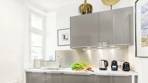 A modern kitchen with stainless steel appliances, a window, and a framed picture on the wall.