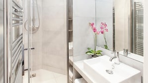 Ein modernes Badezimmer mit begehbarer Dusche, einem weißen Waschbecken und einem Spiegel.