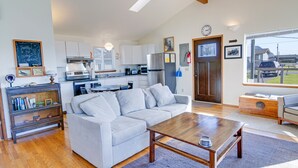 A modern living room with a grey sofa, wooden coffee table, and a kitchen in the background.