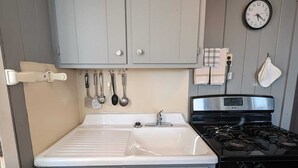 A kitchen with grey cabinets, a stainless steel stove, and a white sink.