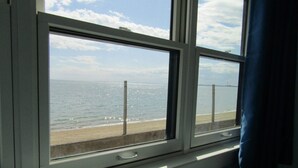 Ein Zimmer mit großem Fenster und Blick auf einen Strand.