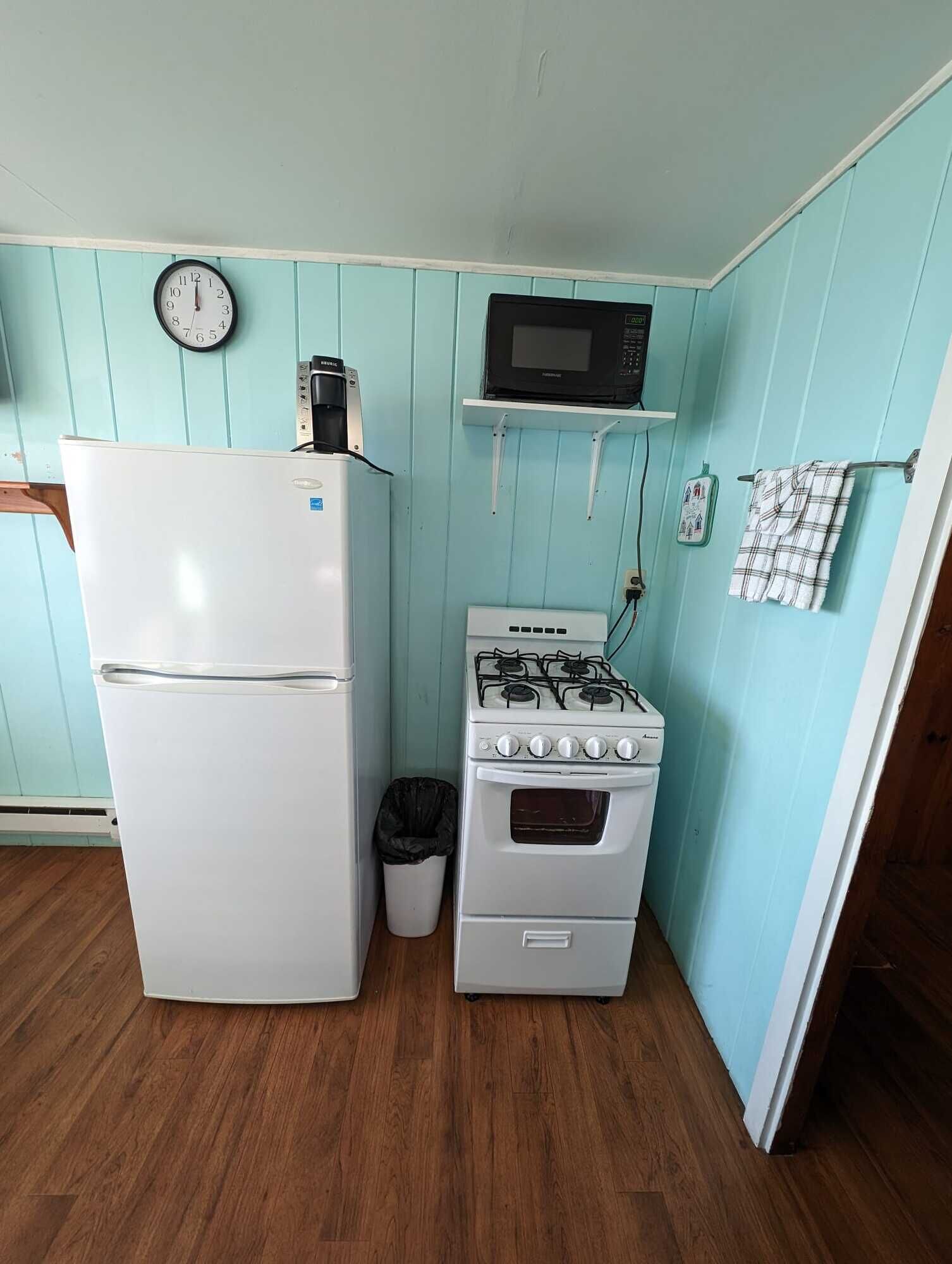 Una cocina compacta con un refrigerador blanco, una estufa y un microondas sobre una repisa.