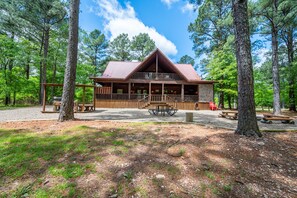 A lodge with a wooden exterior, a balcony, and a gravel driveway.