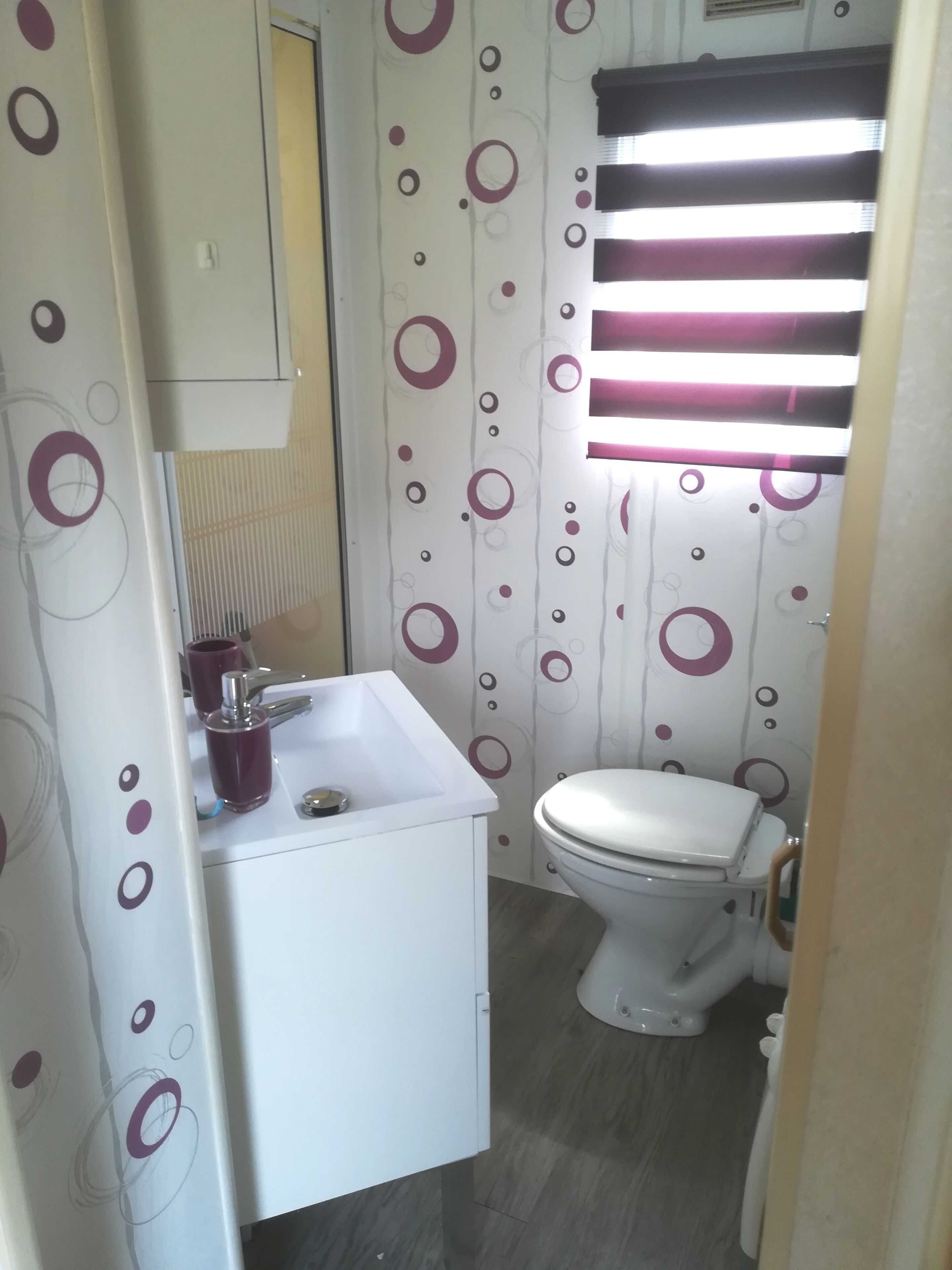 A bathroom with a white sink, a toilet, and a window with horizontal blinds.