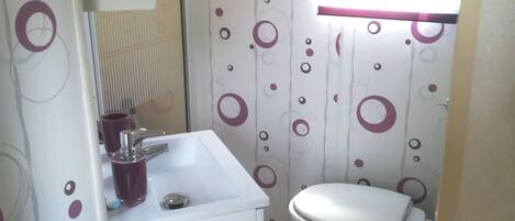 A bathroom with a white sink, a toilet, and a window with horizontal blinds.
