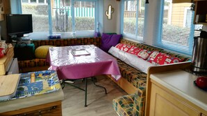 Een knus woongedeelte met een kitchenette, een eethoek en een zithoek met een tafel met tafelkleed.