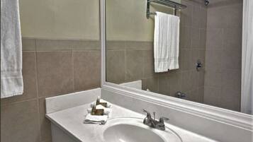 A bathroom with a large mirror, a sink, and a shower area.