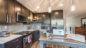 Une cuisine moderne avec des meubles en bois foncé, des appareils électroménagers en acier inoxydable et un îlot central doté de sièges.