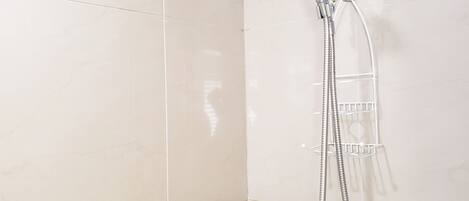 A shower with a handheld showerhead and a wall-mounted faucet.