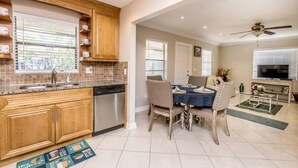 Een moderne keuken met houten kastjes, een vaatwasser en een eethoek met een tafel en stoelen.