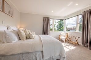 A bedroom with a large bed, a chair, a window, and a view of greenery. - Redwoods Haven - Spa Pool, Sleeps 9 (Rotorua)