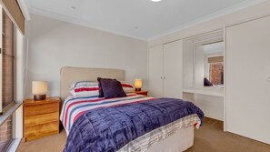 Une chambre à coucher avec un lit, des lampes de chevet, une fenêtre et une armoire.