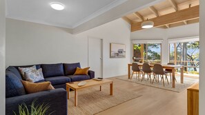 A modern living room with a sofa, coffee table, and dining area with chairs.