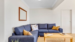 A modern living room with a sectional sofa, a coffee table, and a framed picture on the wall.