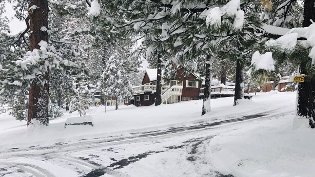 Una calle cubierta de nieve con casas y árboles.