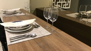 Taula de menjador coberta amb plats, coberts i vasos de vi, amb un panell decoratiu al fons.