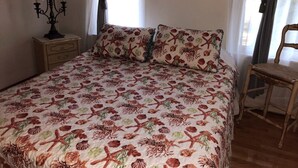 A bedroom with a bed, a nightstand, a chair, and a lamp. - Cozy Apartment on Cape Cod MA (Mashpee)