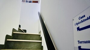 Un escalier muni d’une rampe et d’un panneau indiquant les directions vers « Casa i Spicchite » et « Terrazza ».