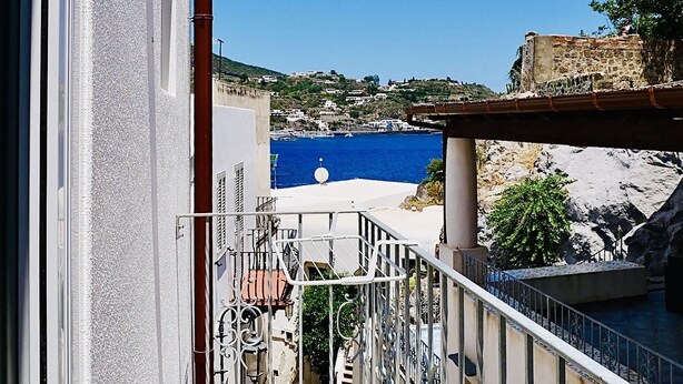 Un balcon avec vue sur la mer et un bâtiment en pierre.