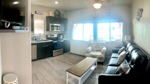 A compact living space with a kitchenette, a sofa, and a coffee table. - The Beachfront Villa 13 (Earp)