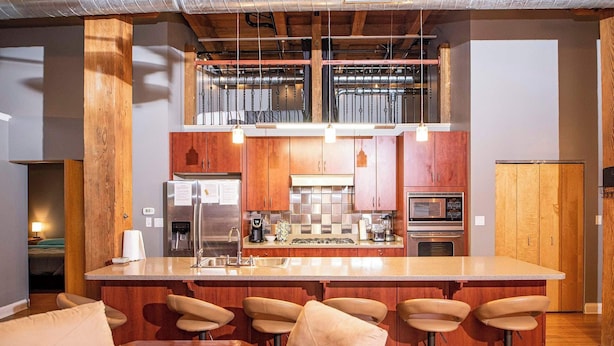 A modern kitchen with a central island, bar stools, and a dining table.